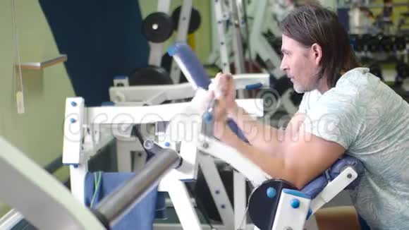在二头肌机上进行大量锻炼中年人在健身房锻炼视频的预览图