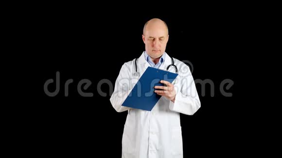 男医生在黑色背景上的剪贴板上写白色外套医生在剪贴板上书写医疗记录视频的预览图