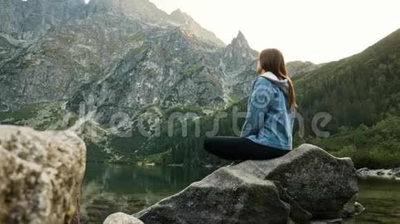 年轻的旅游妇女在一个山湖上休息在山上欣赏风景视频的预览图