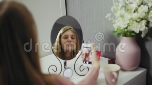 微笑的女人在手机上对着镜子拍照视频的预览图