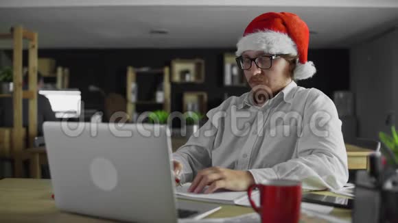 年轻疲惫的经理正在办公室工作在圣诞节喝茶视频的预览图