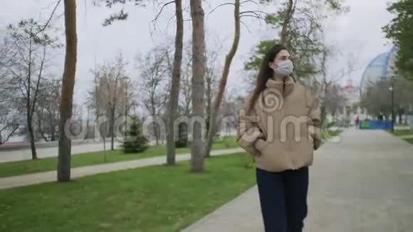 冠状病毒Covid19流行流行Covid19冠状病毒期间带着口罩在公园散步的漂亮女人视频的预览图