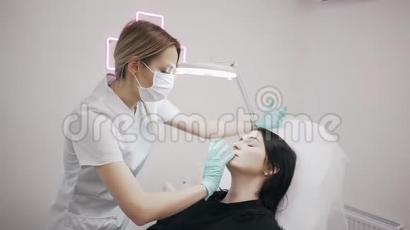 年轻的美容医生准备在女性嘴唇上注射医生美容师做了隆唇手术视频的预览图
