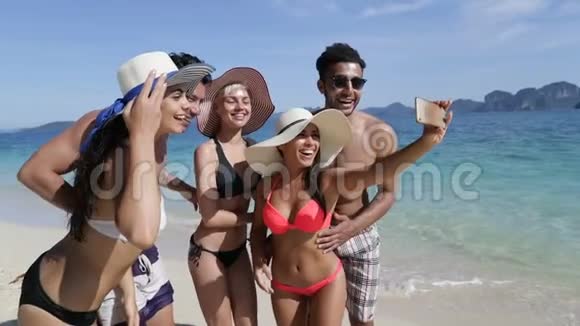 人们在海滩上的手机上自拍在度假时微笑的年轻游客团体视频的预览图