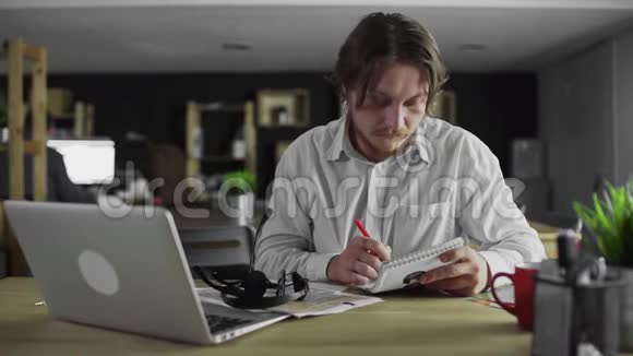年轻的经理坐在办公桌前写字然后离开视频的预览图