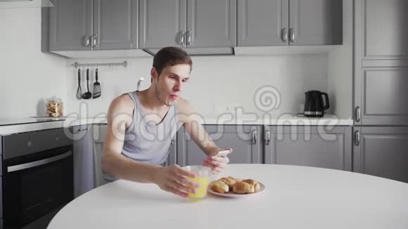 年轻人喝橙汁手里拿着智能设备每天早上都有帅哥坐在那里视频的预览图