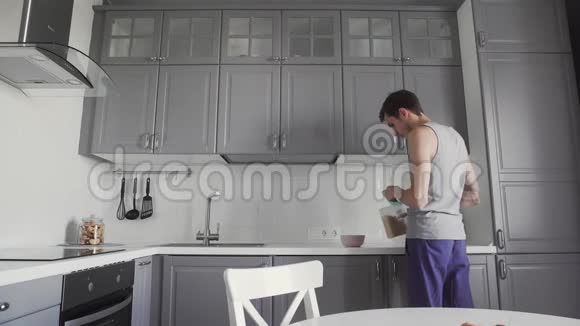 年轻人在厨房准备早餐他把玉米片倒进碗里视频的预览图