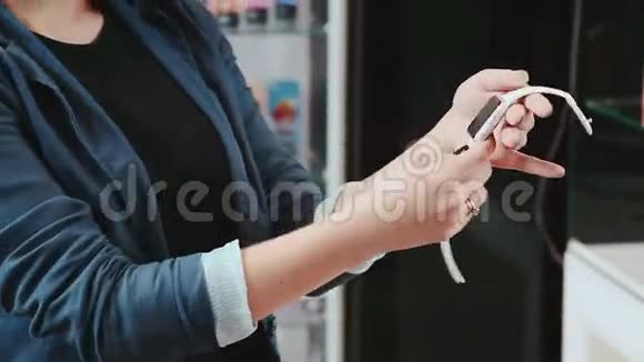 年轻女子在尝试新的智能手表智能手表年轻的女人选择在商店里买智能手表买可穿的视频的预览图