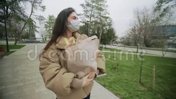穿着防护面罩站在购物袋中的年轻女性在冠状病毒COVID19流行时期视频的预览图