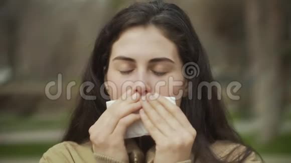 年轻女子在户外擦拭时咳嗽的肖像视频的预览图