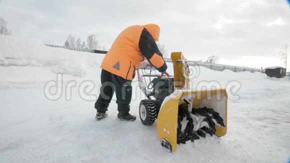 冬天人们穿着一件橘黄色的夹克穿上一件扔雪器视频的预览图