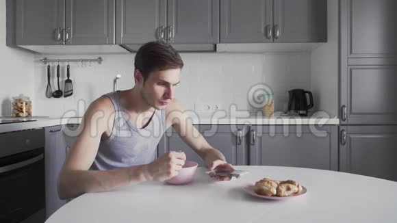 年轻人在厨房里吃汤用电话视频的预览图