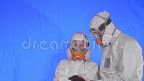 呼吸器的病毒学家用手写笔在平板电脑中写作穿着保护性衣服的男人和女人视频的预览图