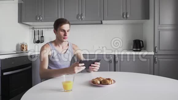 年轻人在家里坐在厨房里玩电子游戏视频的预览图