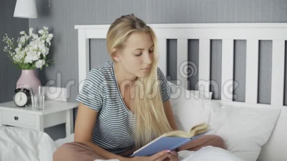 年轻女子在床上看书卧室有复印空间视频的预览图