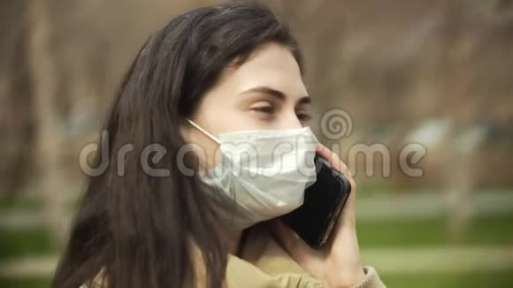 户外年轻女性侧视带医用口罩保护病毒电话交谈冠状病毒概念视频的预览图