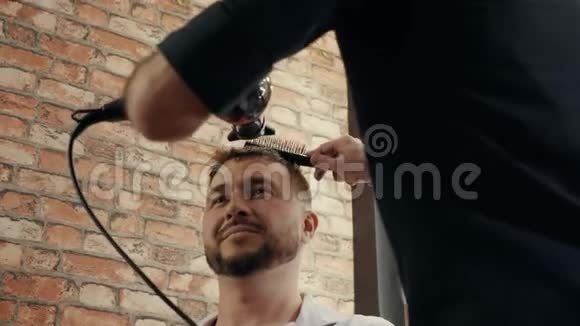 帅哥在理发店晒头发理发器使用吹风机和梳子为男性发型发型师干头发视频的预览图