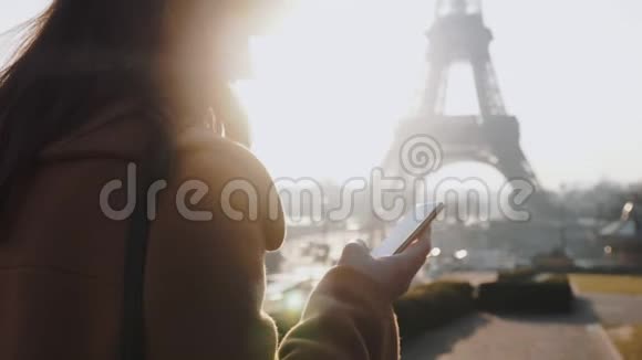 年轻成功的女商人使用手机移动办公应用程序步行在阳光明媚的巴黎埃菲尔铁塔风景慢动作视频的预览图