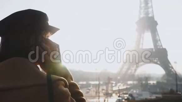 镜头跟随美丽的年轻女商人走着在阳光明媚的巴黎埃菲尔铁塔观景慢动作上打电话视频的预览图