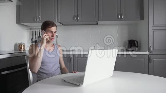自由职业者用手机说话在厨房用笔记本视频的预览图