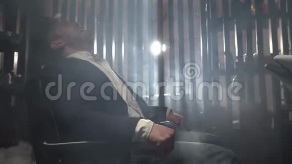 穿着蓝色夹克和白色衬衫的男性商人坐在电动椅子上抽搐对年轻人的折磨视频的预览图