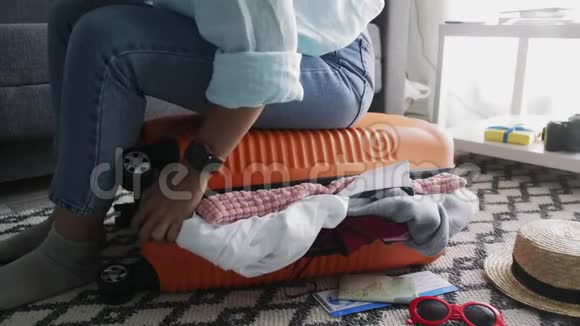 可爱的女孩坐在一个装满东西的手提箱上试图把它关上视频的预览图