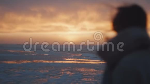 后景快乐的当地女人带着飞扬的头发在寒冷的海边观看史诗般的粉红色日落在度假旅行中慢动作视频的预览图