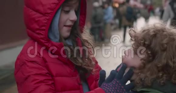 小女孩穿着红色的帕卡鞋在金泽雅普玩着捏着小男孩的脸颊视频的预览图
