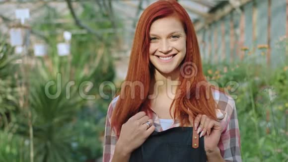 美丽的花匠女人一个红头发的女人正对着镜头微笑双手交叉站在镜头里视频的预览图