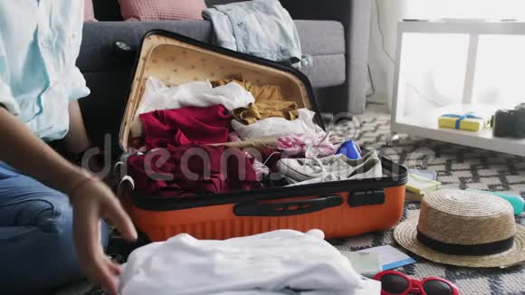 旅行妇女打包旅行箱准备公路旅行准备度假行李把衣服放进袋子里视频的预览图