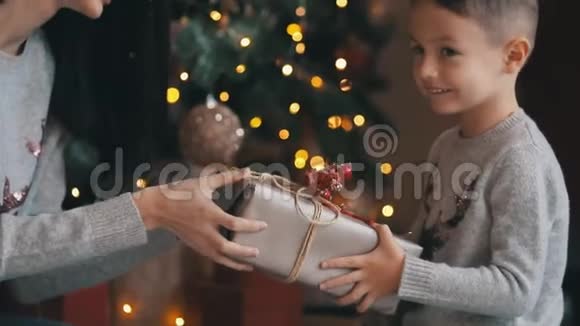 可爱的小男孩在圣诞树附近的礼物中高兴视频的预览图