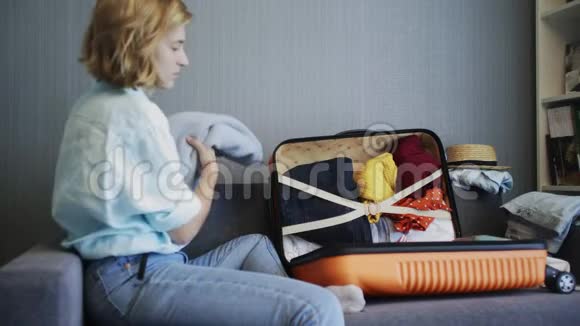 旅行妇女坐在沙发和行李箱边的侧视图准备上路视频的预览图