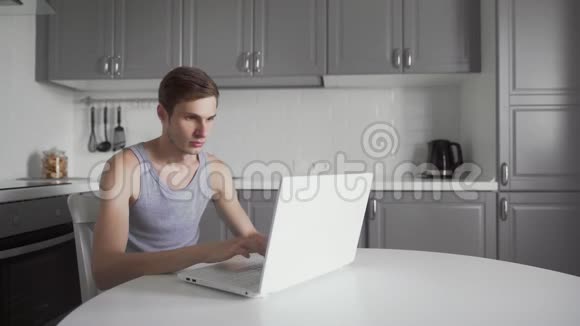 成功的男人在家里使用笔记本电脑时会做赢家手势视频的预览图