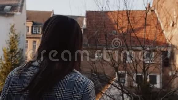电影院后景拍摄年轻快乐的白种人旅游妇女在阳光明媚的老城房子阳台上喝咖啡慢动作视频的预览图