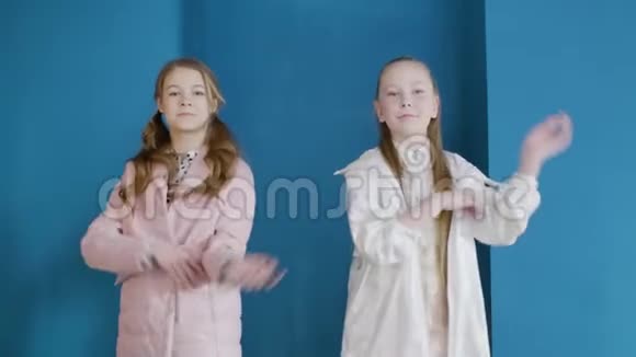 自信的女孩穿着夹克在蓝墙背景上跳舞快乐的少女们在蓝舞的镜头前跳舞视频的预览图