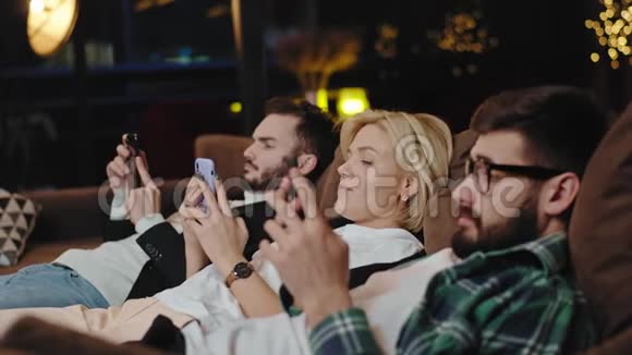 在摄像机前一群年轻人坐在沙发上坐在智能手机上花时间在沙发上视频的预览图