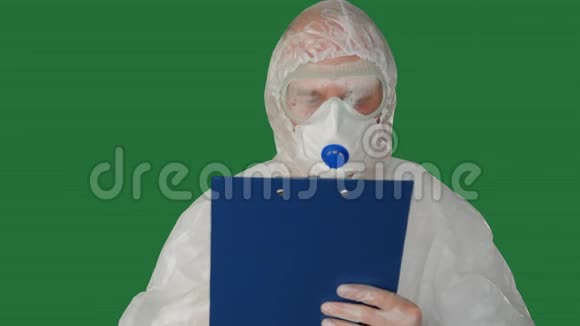 医务人员穿着防护服装在夹板上书写口罩穿着安全套装的男子在夹板上写面具视频的预览图