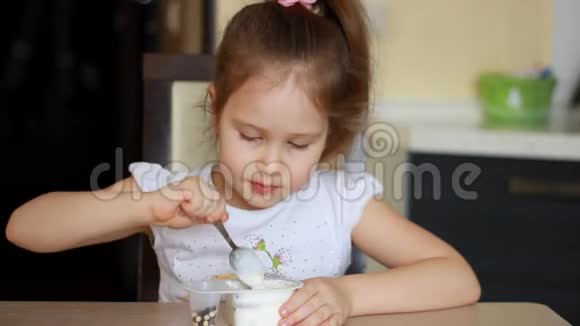 小女孩吃酸奶和奶酪加麦片儿童早餐吃乳制品视频的预览图