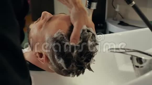 男式发廊用水冲洗男式头发泡沫洗发液清洗男性头部和头发头视频的预览图