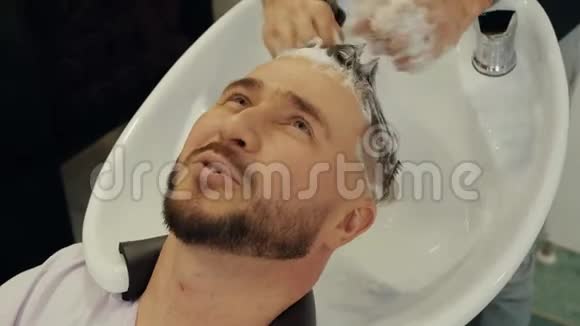 美发店快乐男洗发头理发师用洗发水洗男头视频的预览图