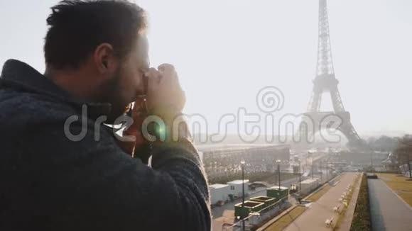 后景快乐自由摄影师男子拍摄巴黎埃菲尔铁塔的照片与复古电影相机慢动作视频的预览图