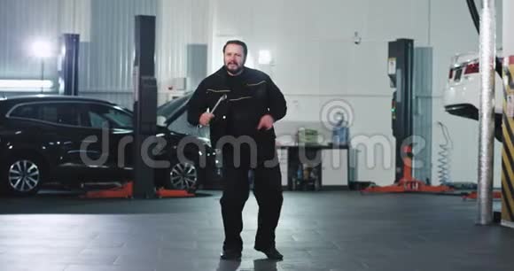 在工作中机械师在完成工作后在汽车服务中心跳舞的时候很开心视频的预览图