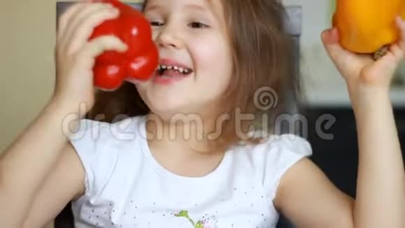 可爱的女婴在厨房吃健康的食物孩子在玩红辣椒和黄椒维生素的概念视频的预览图