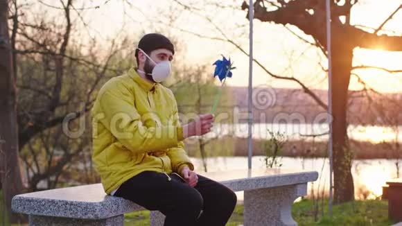 健康和安全的生活理念N1H1一个人坐在公园的椅子上脸上戴着防护面具他在玩视频的预览图