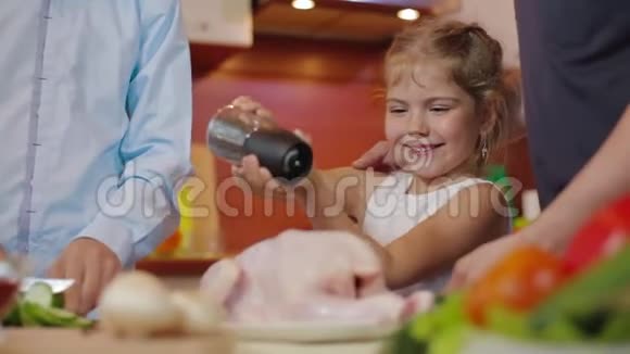 小女孩用胡椒粉撒鸡肉快乐的一家人一起在厨房做饭父母教有趣的东西视频的预览图