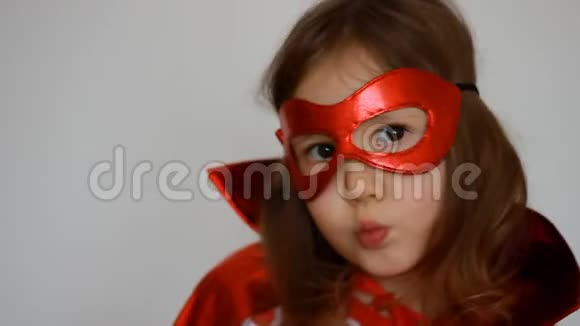 特写肖像女婴扮演超级英雄有趣的孩子穿着红色雨衣和面具玩权力超级英雄超级英雄视频的预览图