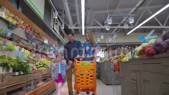 有小女儿的年轻父母在一家大型超市里选择新鲜水果商场超市销售购物视频的预览图