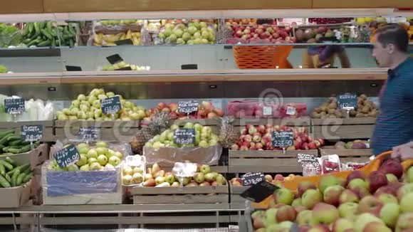 年轻夫妇在一家大型超市里选择新鲜水果挑选新鲜香蕉的人在杂货店超市出售视频的预览图