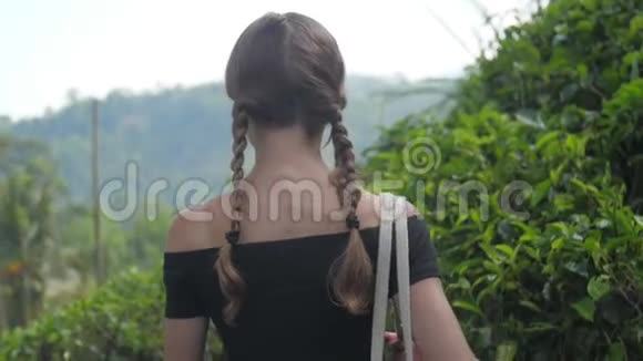 女士沿着绿茶种植园之间的高地小径散步视频的预览图