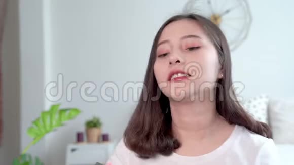 漂亮的亚洲女人用刷子在嘴唇上涂口红来化妆自己视频的预览图